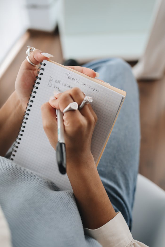 A detailed close-up of a hand with rings writing in a spiral notebook, perfect for educational themes.